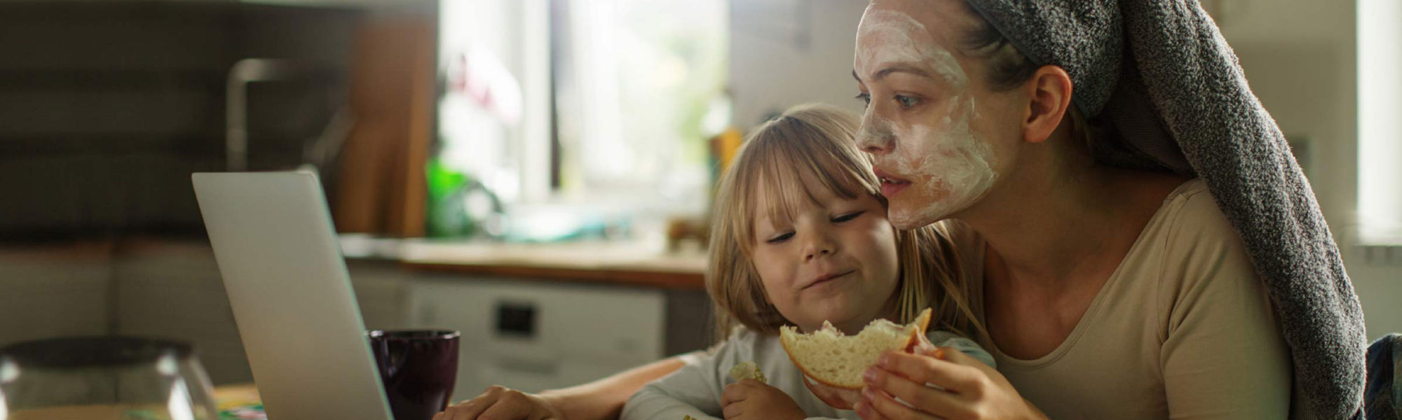 woman working at the computer and with a child resting on her lap, feeding it